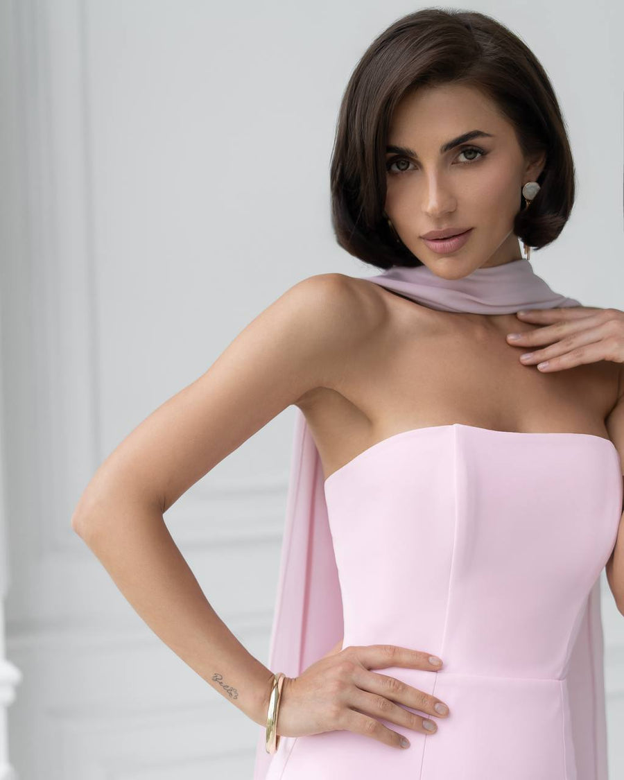Woman wearing a light pink strapless dress with a plain background