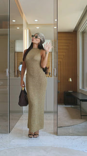 Woman in a long, patterned dress standing in a modern interior setting.