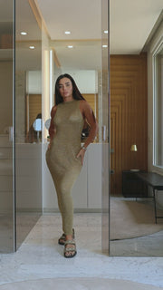 Woman in a long, patterned dress standing in a modern interior setting.