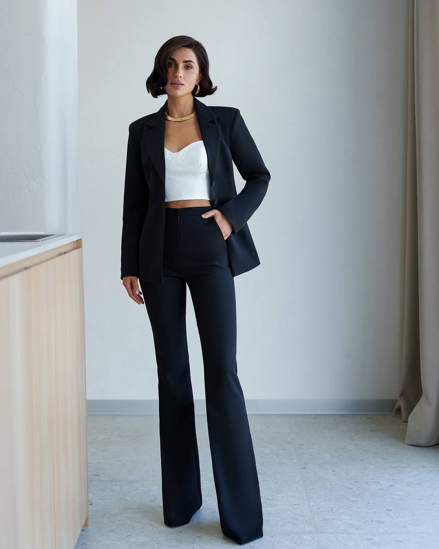 Woman wearing a black suit with a white top in an indoor setting