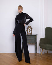 Person wearing a black outfit in a room with a clock and chair.