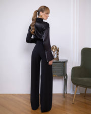 Person wearing a black outfit in a room with a chair and small table.