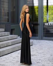 Woman in a black dress standing on a patterned pavement with steps and glass doors in the background.