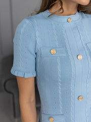 Light blue textured dress with gold buttons on a neutral background