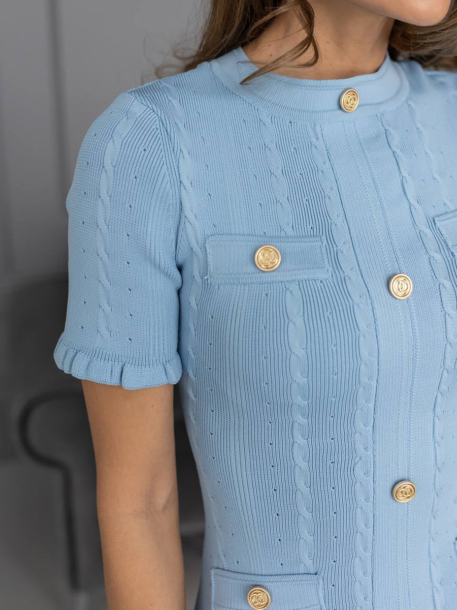 Light blue textured dress with gold buttons on a neutral background