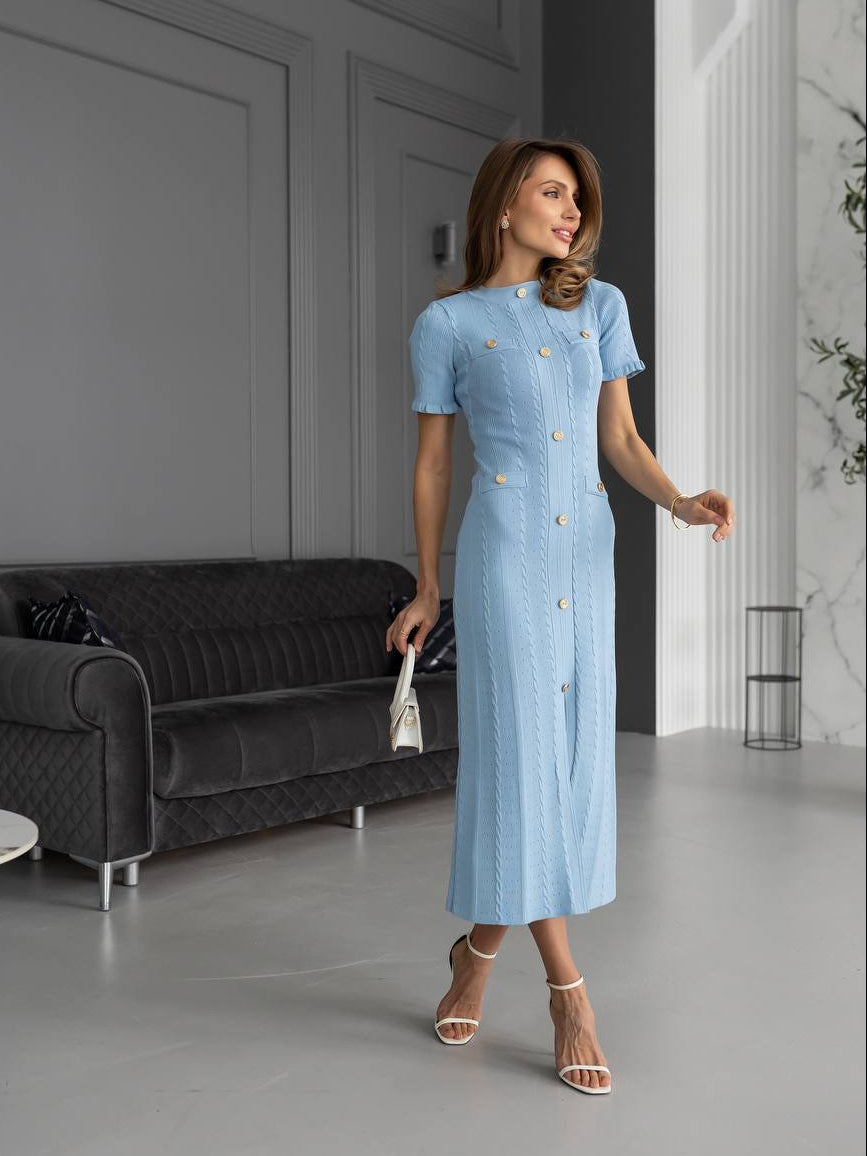 Woman in a light blue dress standing in a modern interior setting.