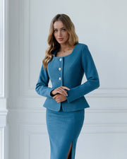 Woman wearing a blue suit standing against a white wall