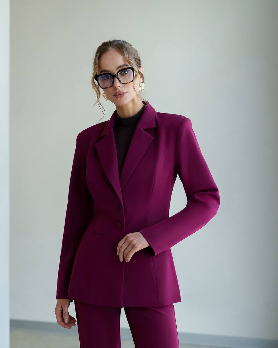 Woman wearing a magenta suit with a plain background