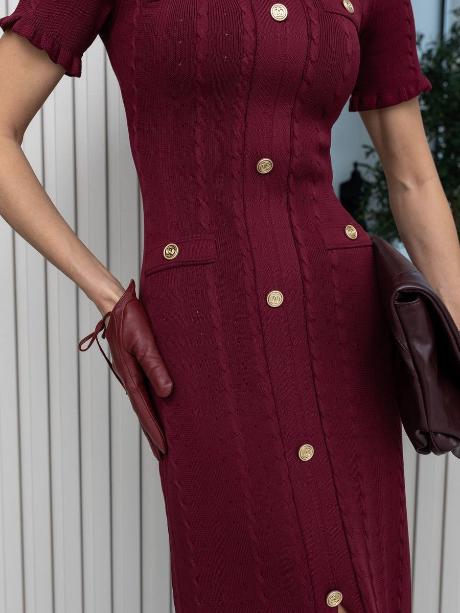 Maroon dress with gold buttons worn by a person, holding a brown leather jacket.