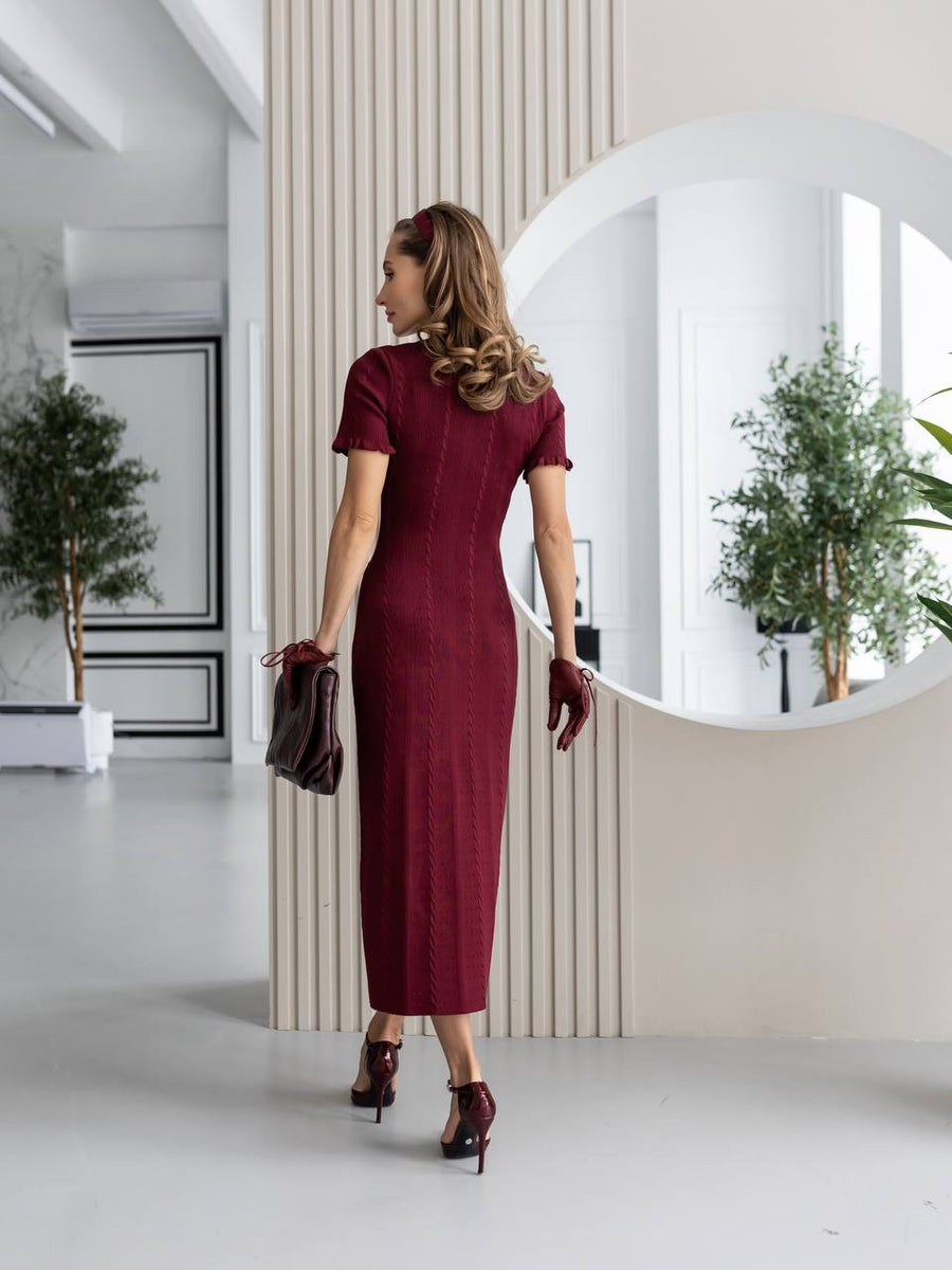 Woman in a burgundy dress standing in a modern interior setting.