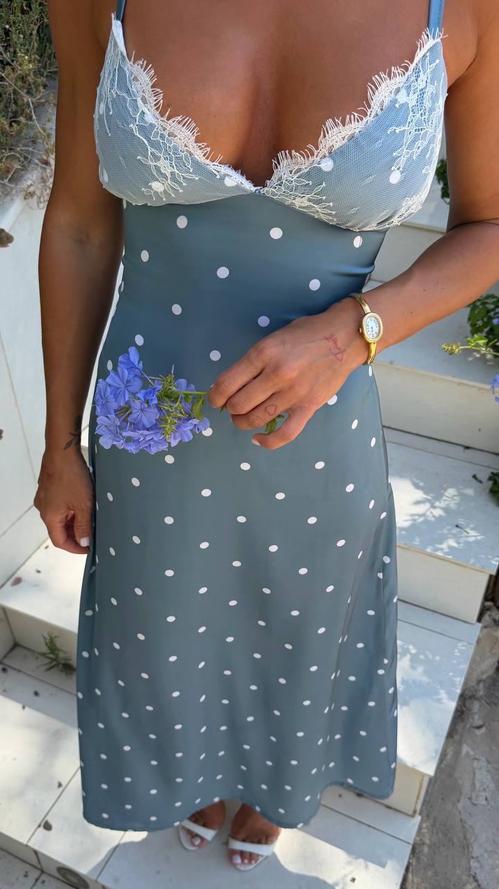 Person wearing a polka dot dress holding flowers outdoors