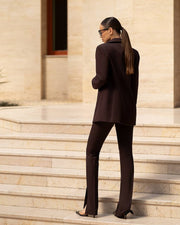 Person in a dark suit standing on stone steps with a building in the background