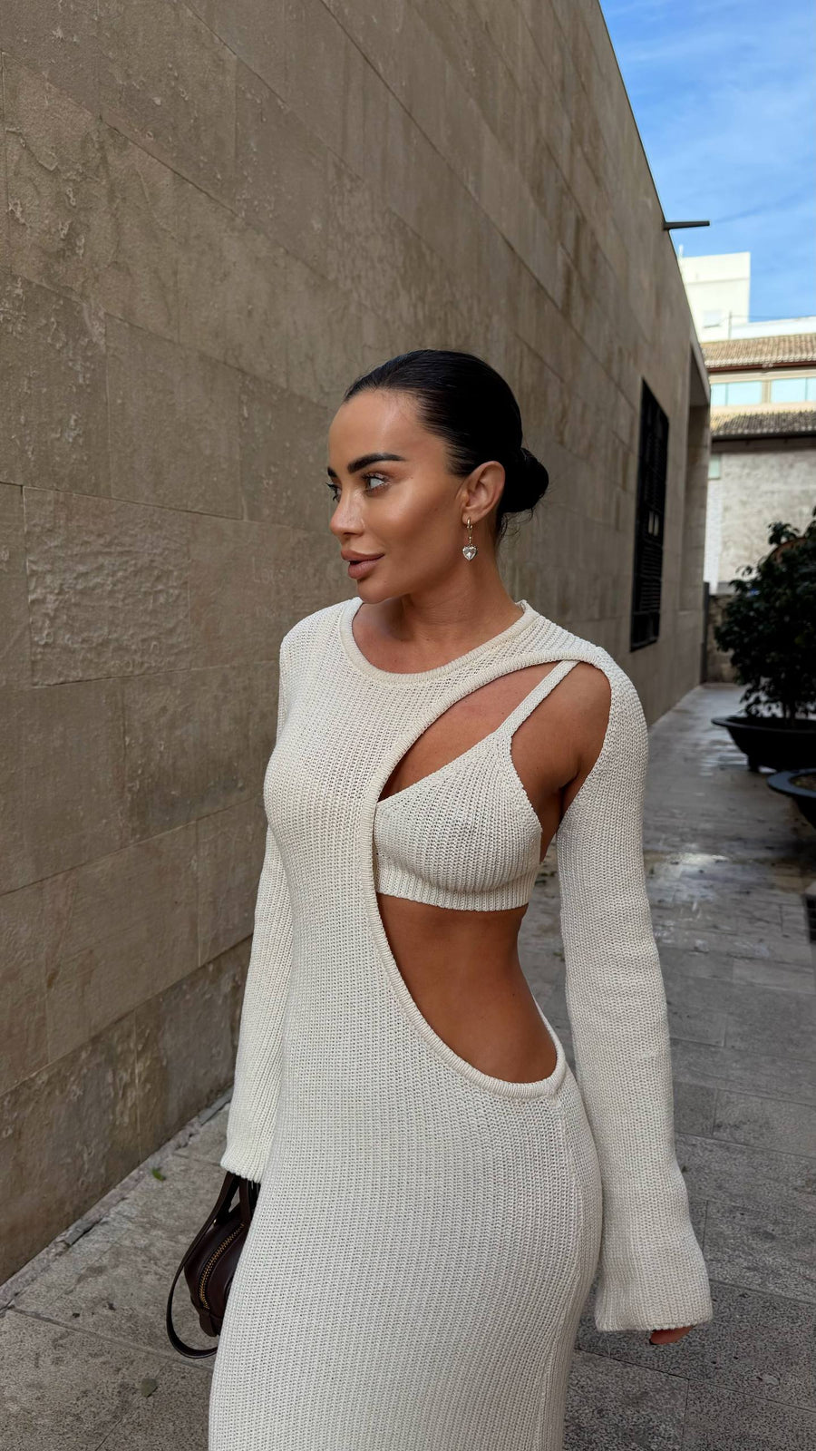 Woman wearing a white ribbed dress with cut-out design outdoors.
