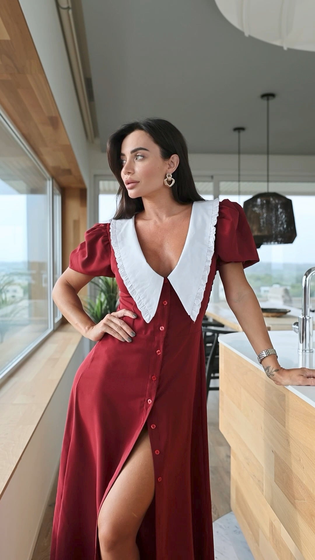 Woman in a red dress with a white collar standing in a modern kitchen.