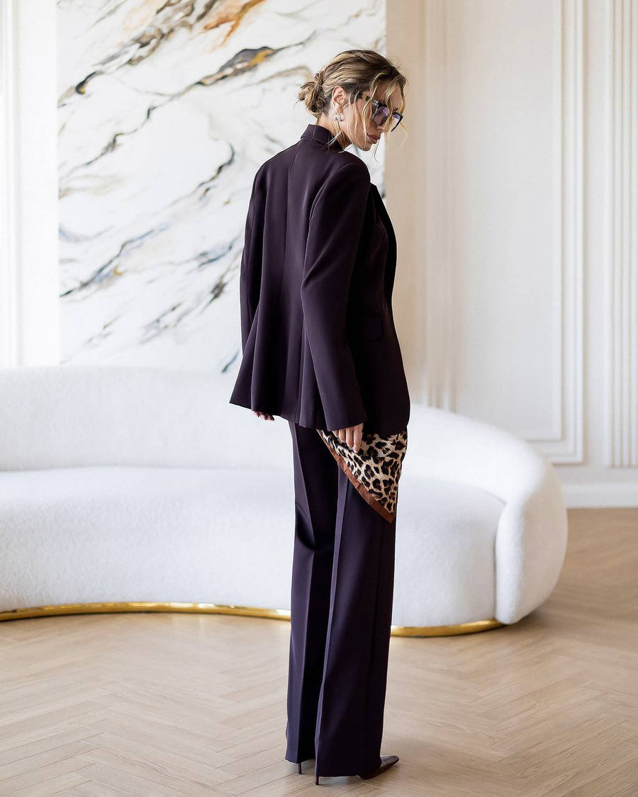 Person wearing a dark purple outfit with a marble wall and white sofa in the background