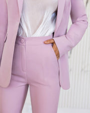 Person wearing a light purple suit with a white top on a neutral background