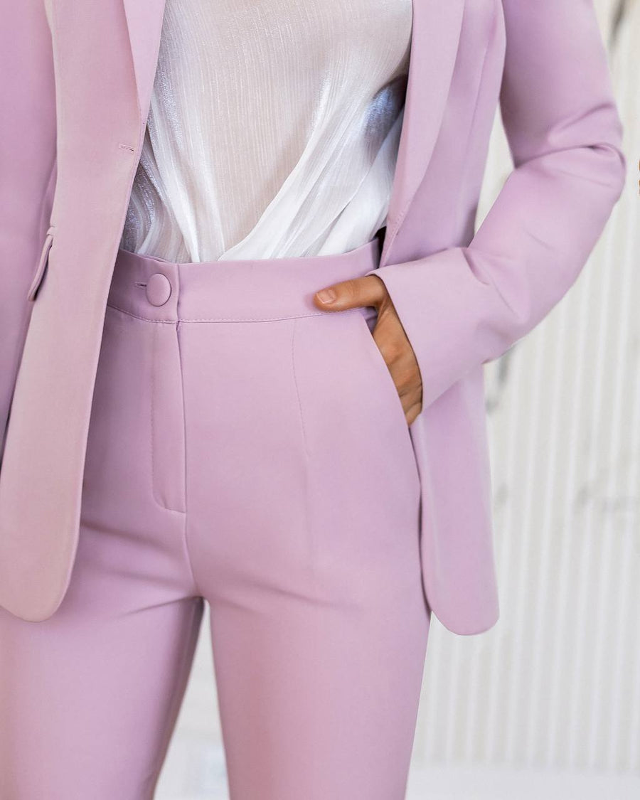 Person wearing a light purple suit with a white top on a neutral background