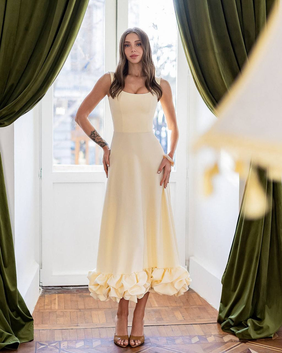 Woman in a yellow dress standing in a room with green curtains.