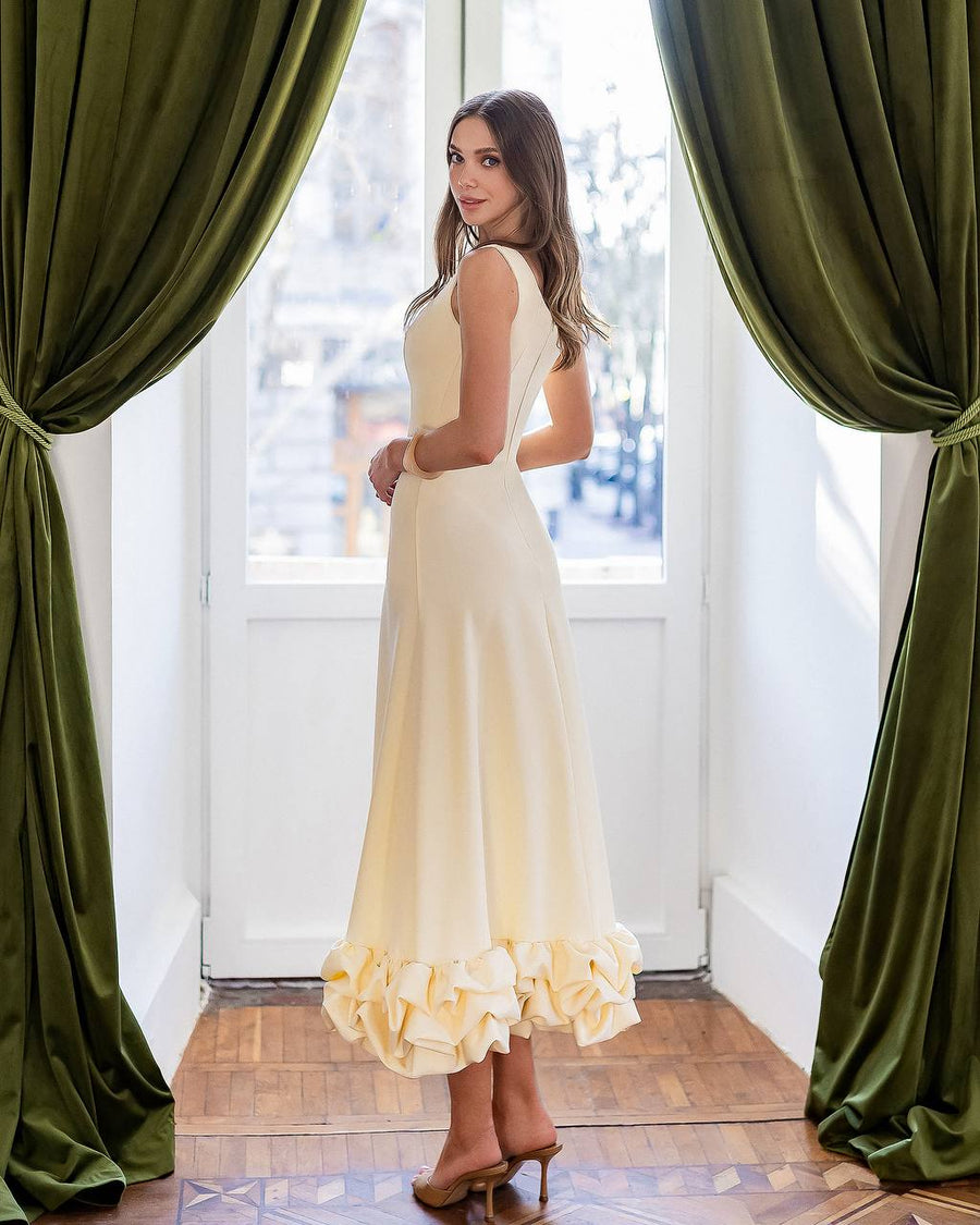 Woman in a yellow dress standing in a room with green curtains.