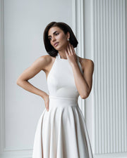 Woman wearing a white dress against a light gray wall
