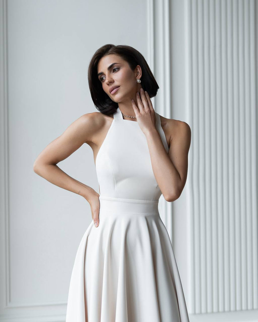 Woman wearing a white dress against a light gray wall