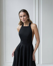 Woman wearing a black dress against a light gray wall