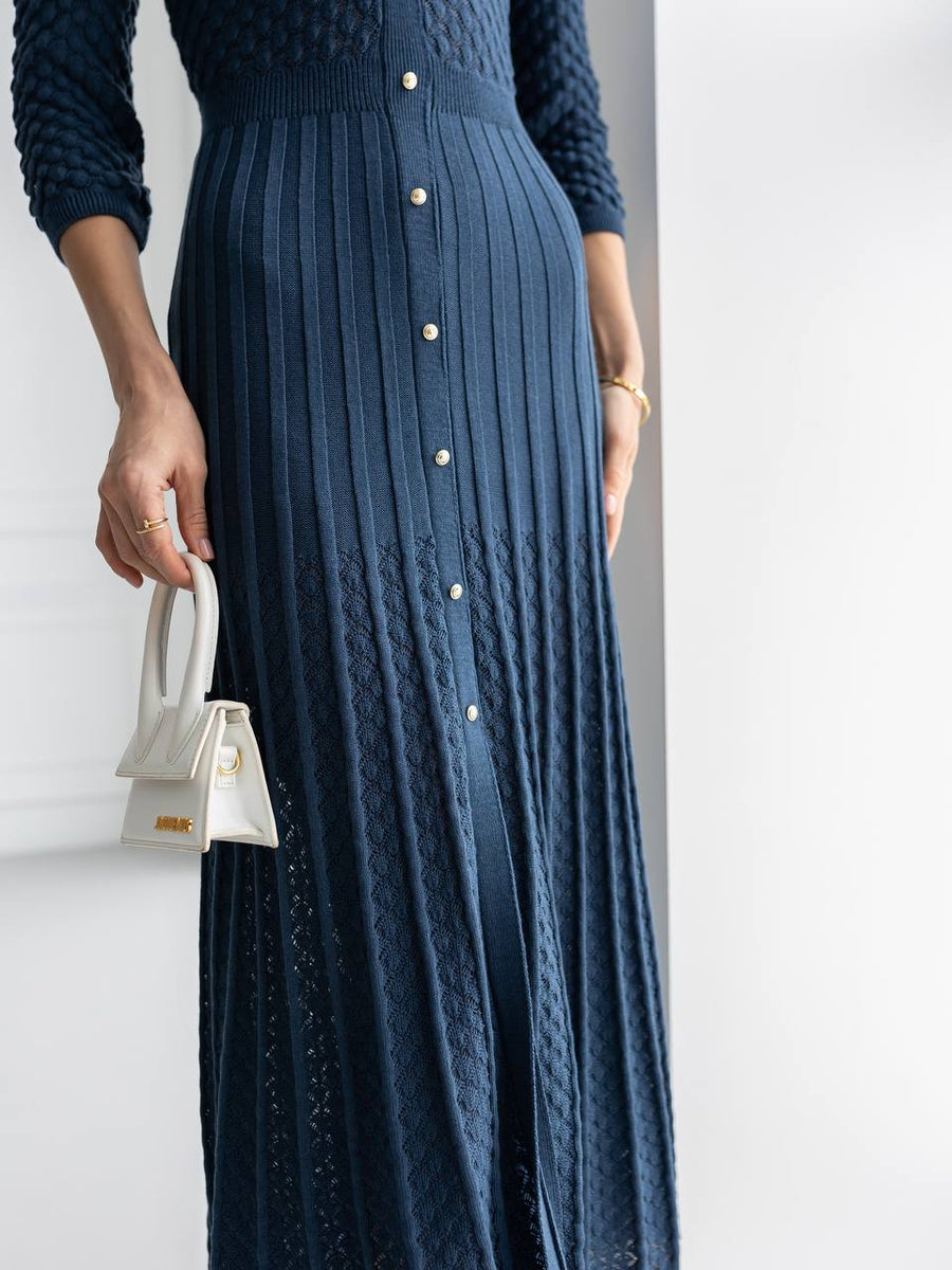 Navy blue ribbed dress with button details on a plain background