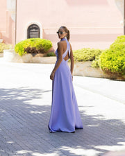 Woman in a lavender evening gown walking on a sunlit path with greenery in the background