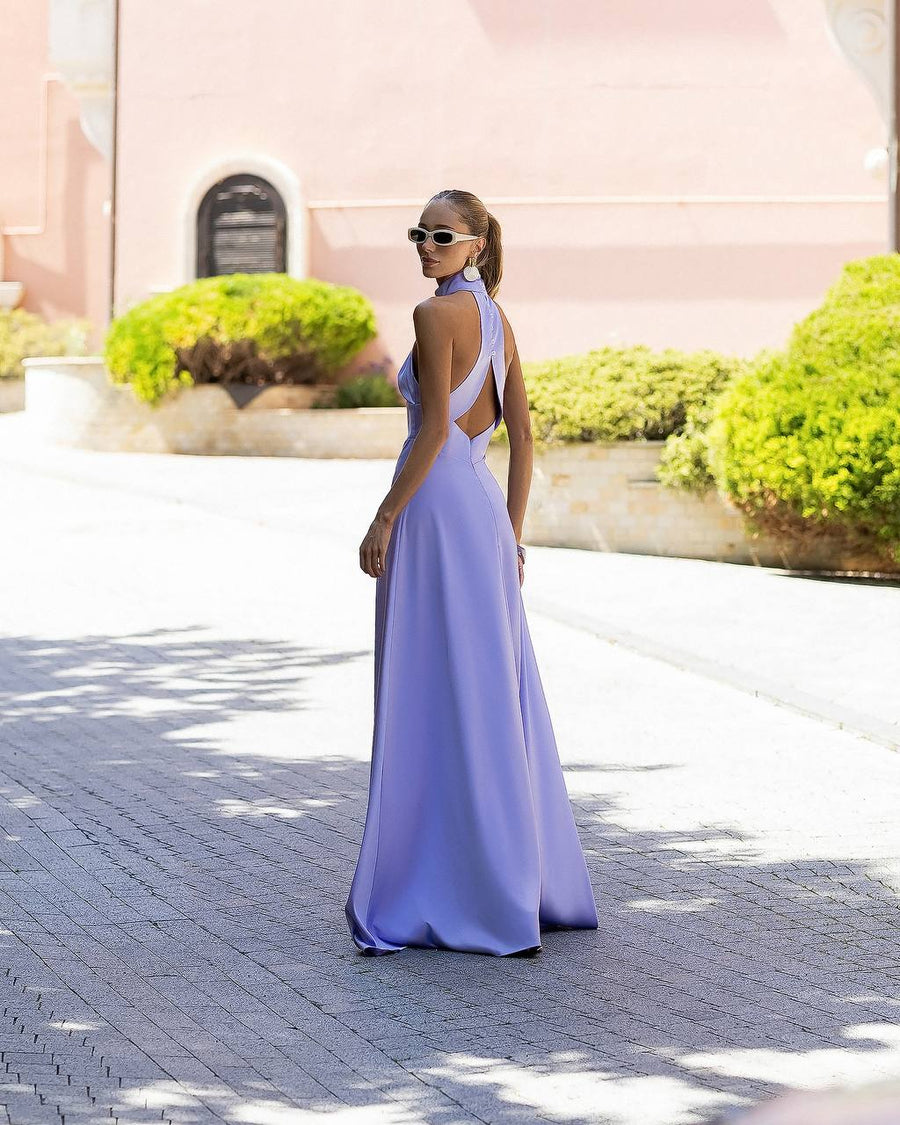 Woman in a lavender evening gown walking on a sunlit path with greenery in the background