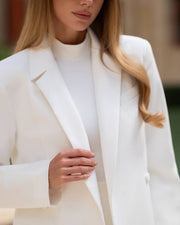 Person wearing a white blazer with a blurred background