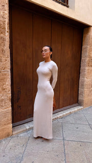 Woman in a long, light-colored dress standing in front of a wooden door.