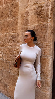 Woman in a white dress standing against a stone wall