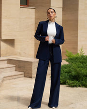 Woman in a navy suit standing outdoors with a building in the background