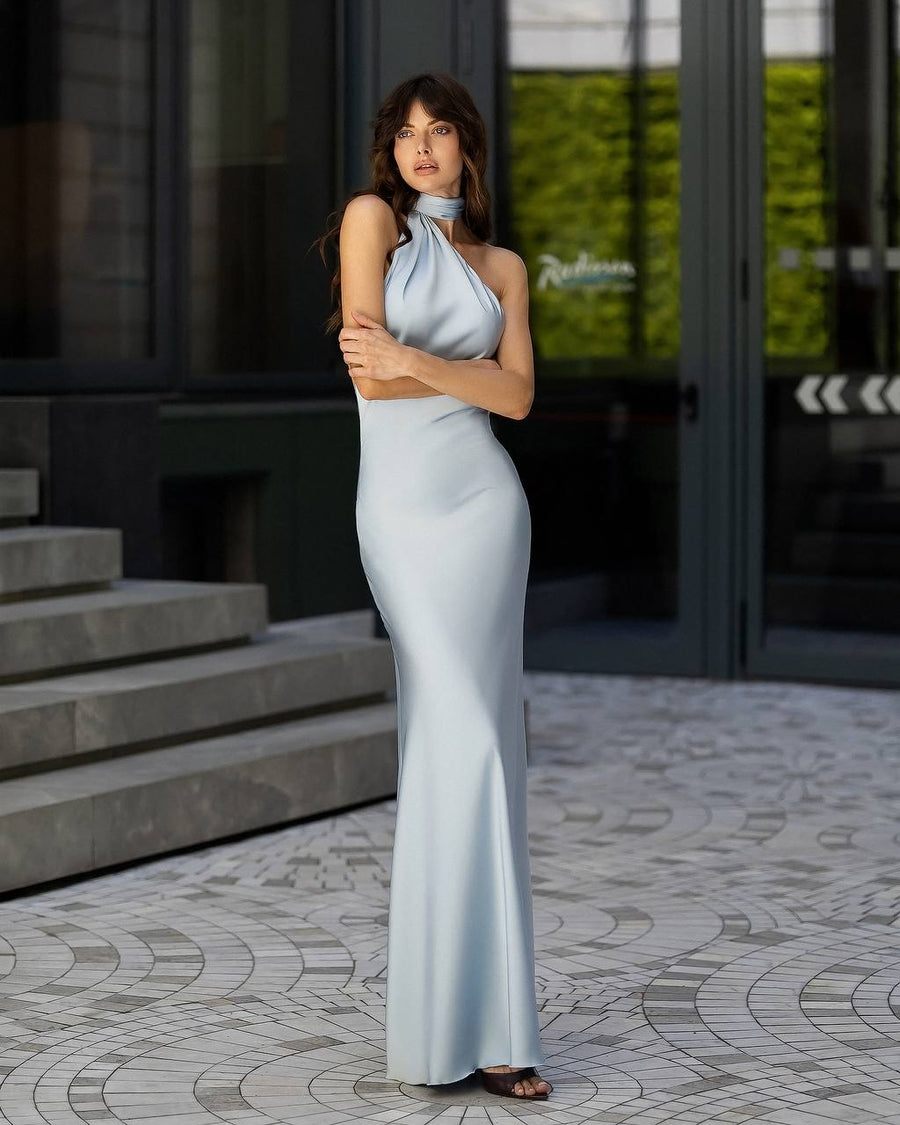 Woman in a light blue evening gown standing on a patterned pavement.