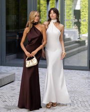 Two women in elegant evening gowns standing outdoors.