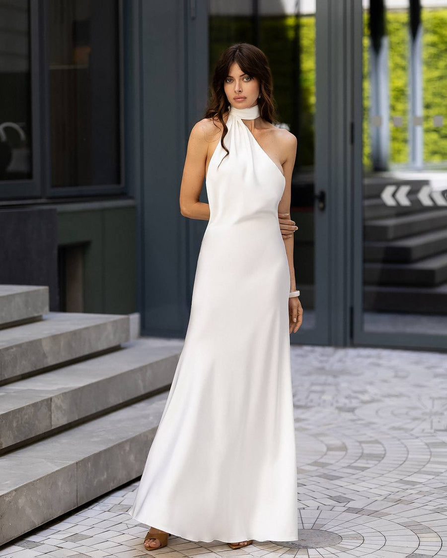 Woman in a white dress standing on a sidewalk with a building in the background