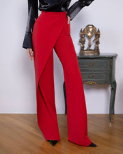 Red pants worn by a person on a wooden floor with a white wall and vintage clock in the background.