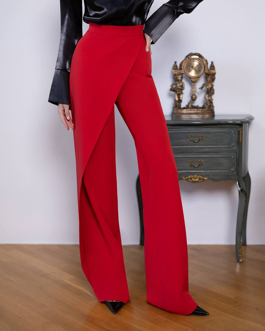 Red pants worn by a person on a wooden floor with a white wall and vintage clock in the background.