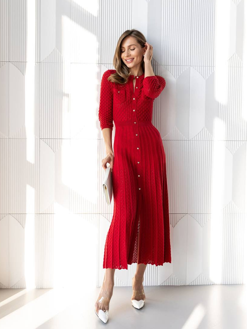 Woman in a red dress standing in a bright room with large windows.