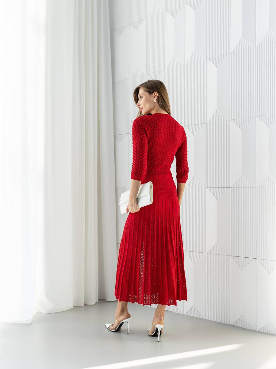 Woman in a red dress standing against a white geometric wall.