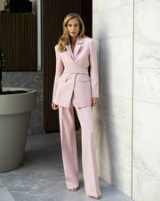Woman in a pink suit standing in a modern indoor setting with a neutral color palette.