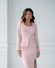 Woman wearing a pink suit against a white wall