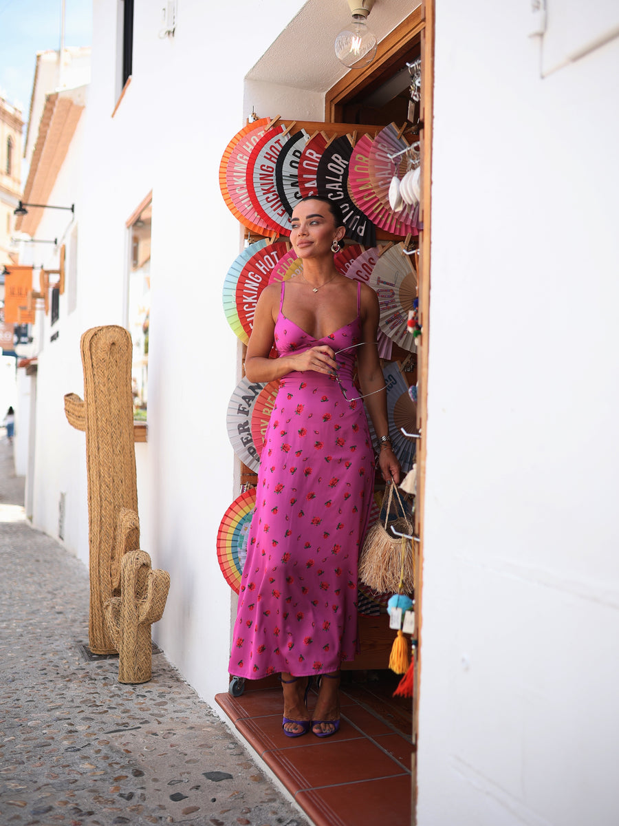 Woman in a pink dress standing in a doorway with colorful fans and a cactus decoration.