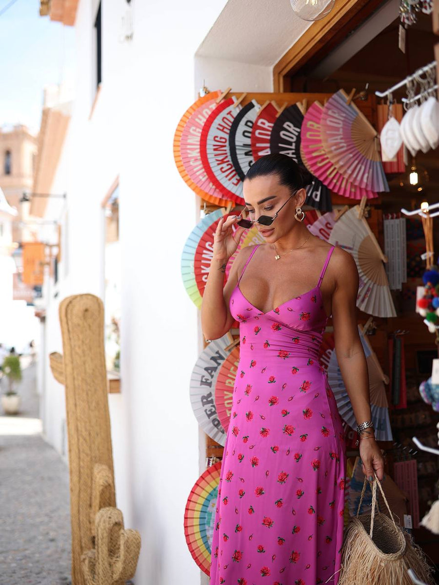Woman in a pink dress standing in front of colorful fans and a store entrance.