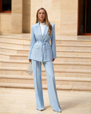 Woman in a light blue suit standing on stone steps.