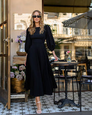 Woman in a black outfit standing in an outdoor cafe setting