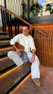 Woman sitting on a staircase holding a guitar in an urban setting