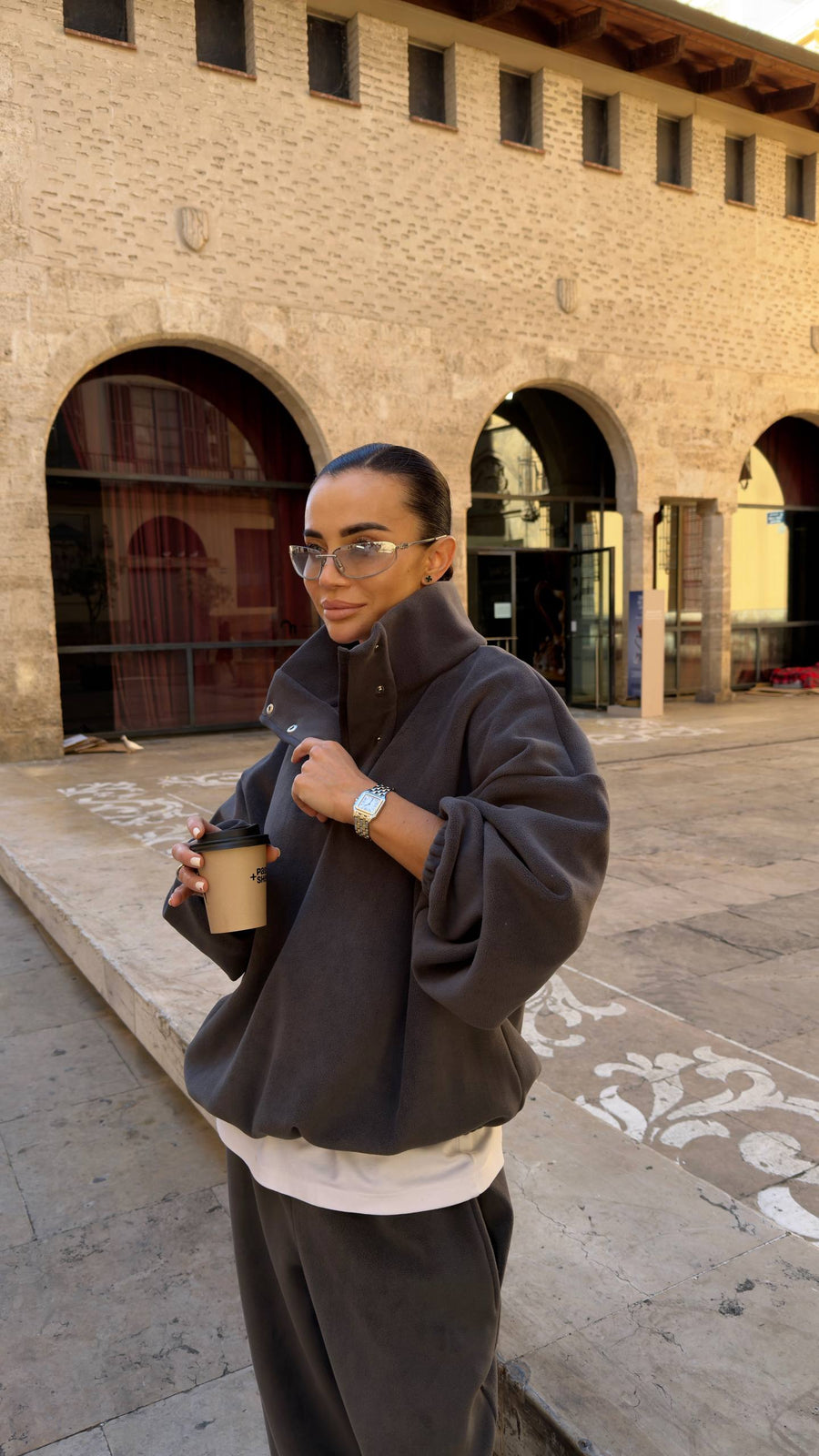 Person holding a coffee cup in front of a historic building