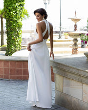 Woman in a white dress standing outdoors with a fountain in the background