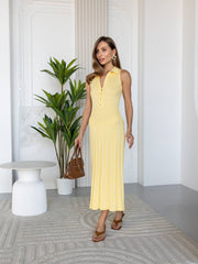 Woman in a yellow dress standing in a modern indoor setting with a plant and table.